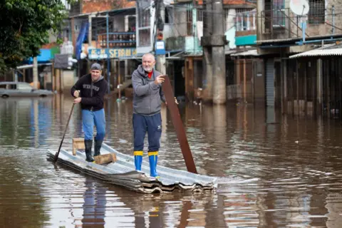 Getty Two men paddle a makeshift canoe down a flooded street in Porto Alegre, Brazil