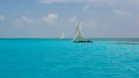 Getty Images Traditional Dhow boats sail off the reef at Mnemba in the azure sea on 12th December 2008 in Zanzibar, Tanzania.