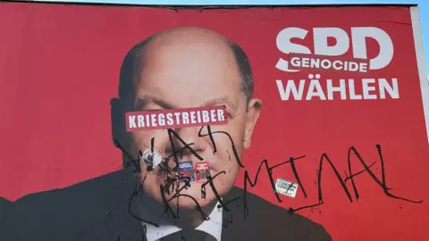 Ali Zaidi/BBC Berlin's graffiti artists label Olaf Scholz a warmonger in German and a war criminal in English