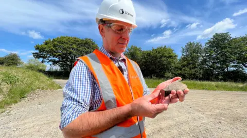 Stuart Woodward/BBC Tim Haines, senior archaeologist, looking at a piece of pottery