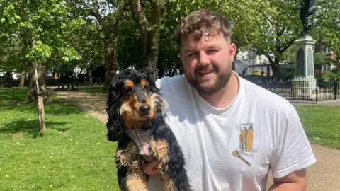 Ben looking at the camera holding his dog