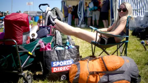 PA Media Girl waits in the sun with all her bags 