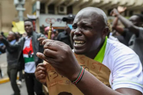 Daniel Irungu/EPA-EFE A Kenyan protester holds a spent bullet