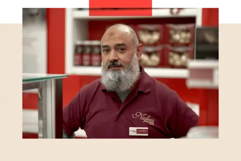 Haji, a man with a beard and a t-shirt, stands in a shop