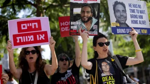 Reuters Families of Israeli hostages held by Hamas hold up placards at a protest calling for their release in Tel Aviv 