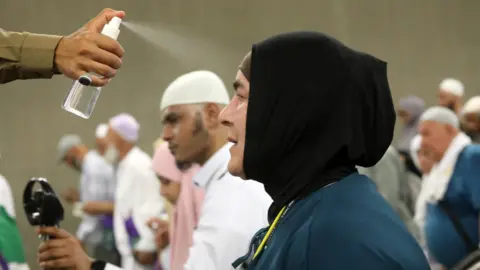 EPA An official sprays water in a woman's face to cool down