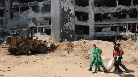 Getty Images Palestinian forensic and civil defence recover bodies at the grounds of Al-Shifa hospital