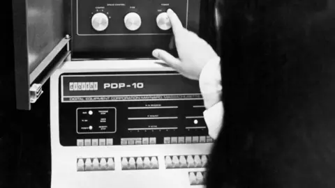 Getty Images A woman shows the dials on a 1969 PDP-10 computer