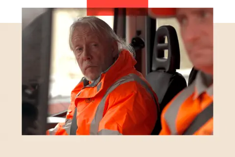 Two men in high-vis jackets in the cab of their bin truck