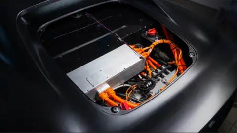 Nyobolt The inside of a sports car - lots of wires and cables neatly organised around a large metallic rectangle