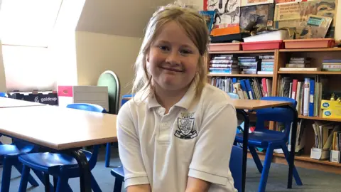 Nine year old Megan sitting on a blue chair in the History room. 