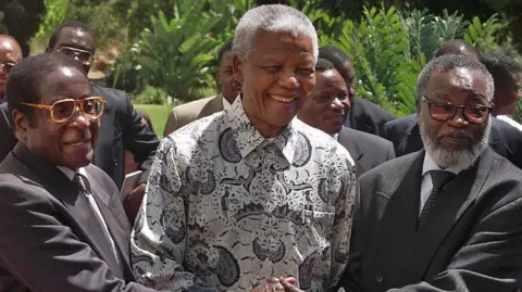 AFP South African President Nelson Mandela (C) and his counterparts, Zimbabwean President Robert Mugabe (L) and Namibia's Sam Nujoma (R), shake hands after a joint press conference in Pretoria, 05 March 1999.