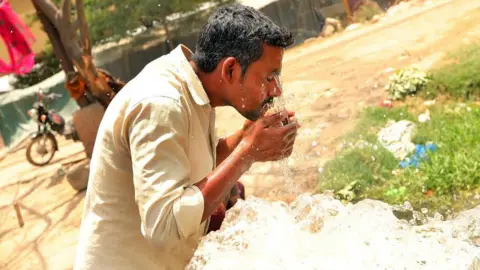 EPA A man splashes his face with water to cool him down on a hot day in India