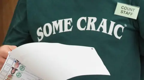 PA A man wearing a jumper saying 'some craic' tallies ballots