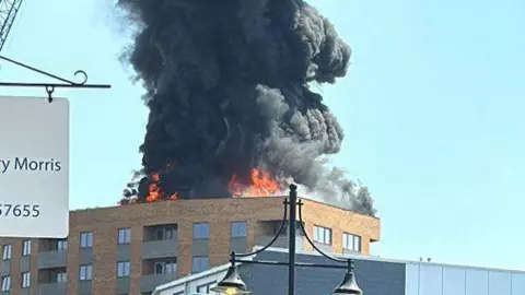 Al Cena flames are seen on the top of a building