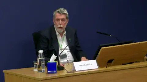 BBC Gareth Jenkins sitting in front of the desk in the room where the Post Office inquiry is being held