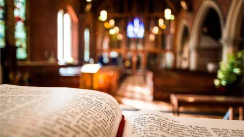 Getty Images Religious book open in foreground with church pews in the background