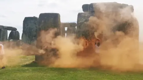 Just Stop Oil Stonehenge with a cloud of orange paint