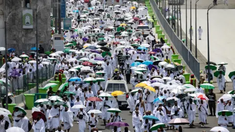 Getty Images People arriving at the Mina tent camp carying sun umbrellas