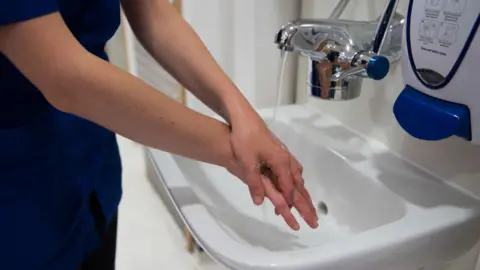 Getty Images Nurse washing hands in sink on hospital ward