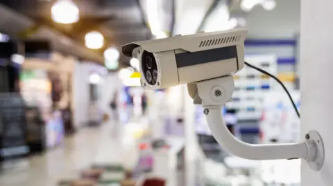 Getty Images CCTV camera in the foreground with a blurred shopping centre seen in the background