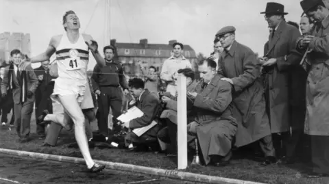 Getty Images Sir Roger Bannister about to cross the tape at the end of his record breaking mile run at Iffley Road, Oxford in 1954.