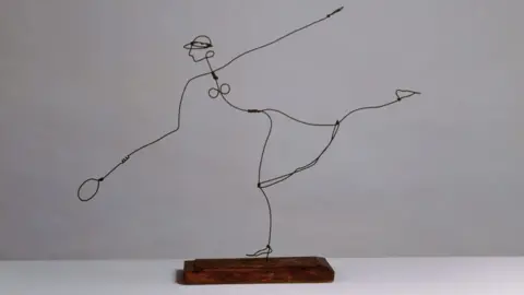 Calder Foundation, New York / DACS, London A wire sculpture attached to a wooden base showing the outline of a woman tennis player leaping to reach a ball, 1927 