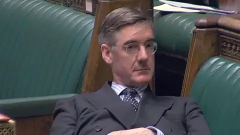 Sir Jacob Rees-Mogg lying back on green leather couches in the House of Commons