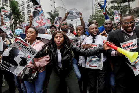 TONY KARUMBA/AFP People chant and hold posters. A woman at the front of the group has a vuvuzela in Nairobi, Kenya - Wednesday 24 July 2024