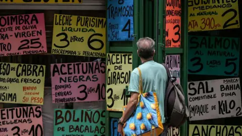 AFP A man looks at food prices outside a Caracas supermarket, 8 May 2024