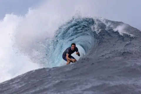 SEAN M HAFFEY/GETTY IMAGES Moroccan Ramzi Boukhiam surfs inside the barrel of a wave. The water appears to curl around him in Tahiti - Wednesday 24 July 2024 