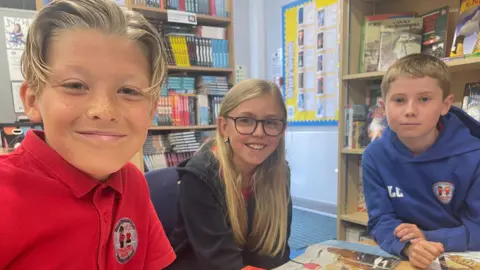 Three pupils smiling and looking at the camera