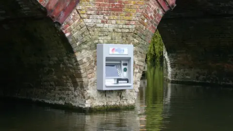 Impro A close up of the cash machine, which has a screen, buttons, slots for bank cards and the dispensing of cash, with Impro Solutions logos at the top and bottom