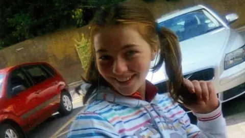 Family A young girl in a striped top with auburn hair in pigtails