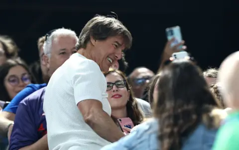 Getty Images Tom Cruise greets fans during the Artistic Gymnastics Women's Qualification 