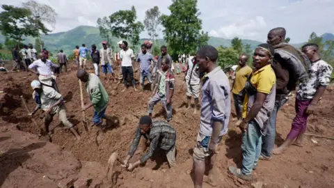 Amensisa Ifa/BBC Group of people digging in the mud