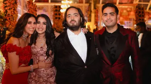 Reuters Akash Ambani and Anant Ambani, sons of Mukesh Ambani, the Chairman of Reliance Industries, pose with Shloka Mehta Ambani, wife of Akash, and Radhika Merchant, daughter of industrialist Viren Merchant, during pre-wedding celebrations of Anant and Radhika in Jamnagar, Gujarat, India, March 2, 2024. Reliance