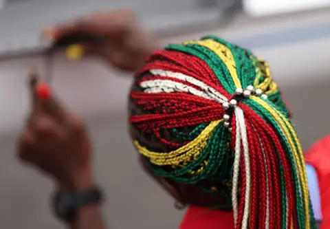 ALEX DAVIDSON/GETTY IMAGES Togolese rower Akoko Komlanvi wears matching braids and nails in green s she builds her boat ahead of a rowing event at Vaires-Sur-Marne Nautical Stadium - 24 July 2024 in Paris, France