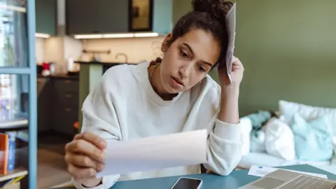 Getty Images A woman looking at her water bill