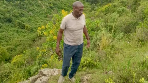 Patrick Mwathi A man standing among green plants