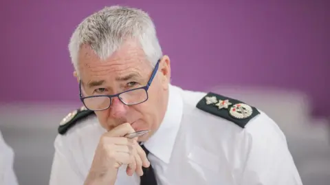 PA Media A man with grey hair and glasses in a police uniform