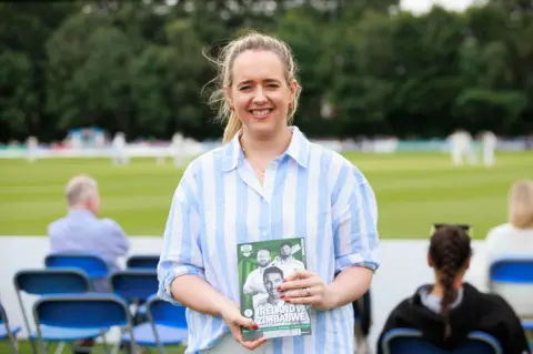 PA Kate Nicholl standing at the test match holding a Ireland Zimbabwe flyer 