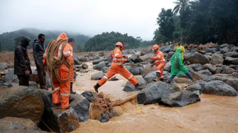 Reuters Members of rescue teams move towards a landslide site after multiple landslides in the hills in Wayanad