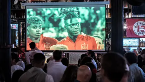 Getty Images People watching a Euro football match on a TV screen