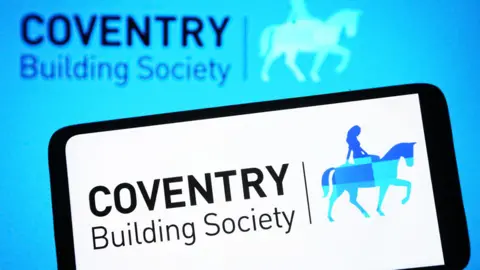 Getty Images Coventry Building Society logo on a smartphone, with the firm's sign in the background