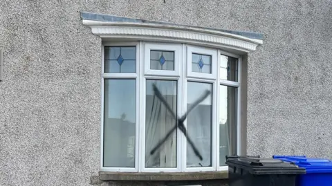 BBC A black X was sprayed across the front window of the house