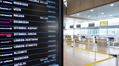 Getty Images Departure boards at Cologne Airport showing cancellations and disruptions