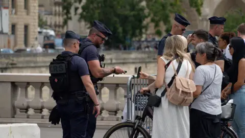 BBC People queue to get through a checkpoint in Paris