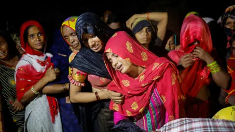 Reuters People mourn the deaths of relatives at a religious event in India, July 2024