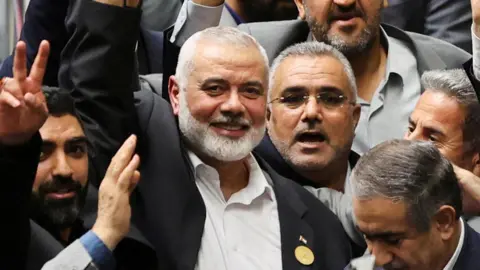 West Asia News Agency via Reuters Ismael Haniyeh smiling with arm raised in the middle of crowd of people